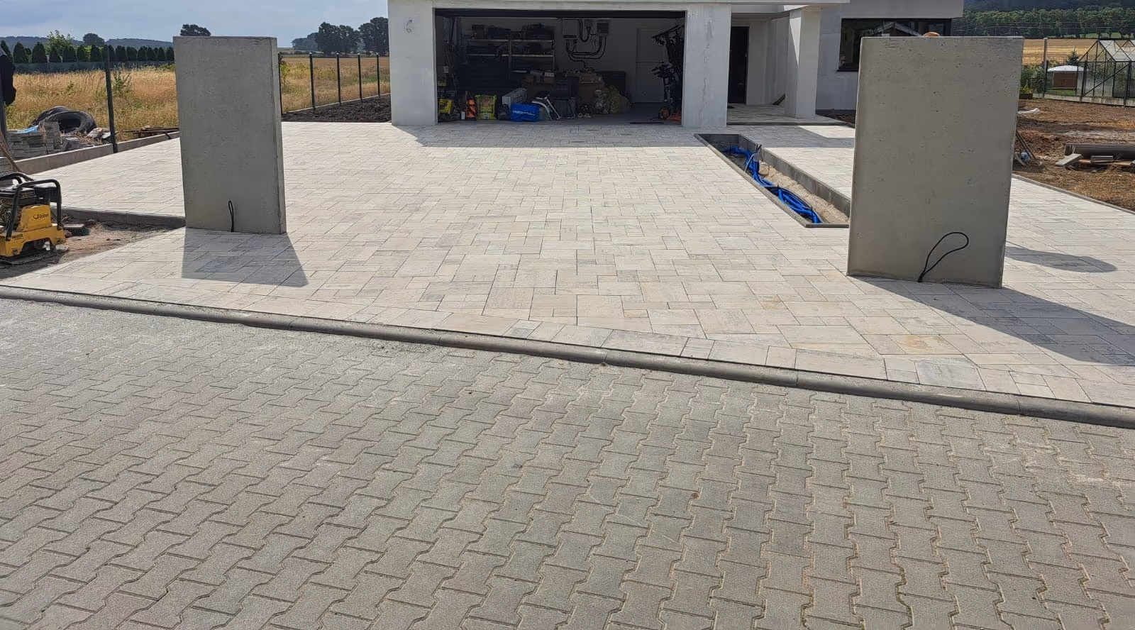Podjazd i plac manewrowy z jasnej kostki przed garażem trzystanowiskowym